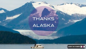 mountain in background with lake and boat in foreground, circle text saying thank you alaska