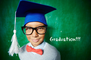 boy wearing graduation hat in front of chalkboard